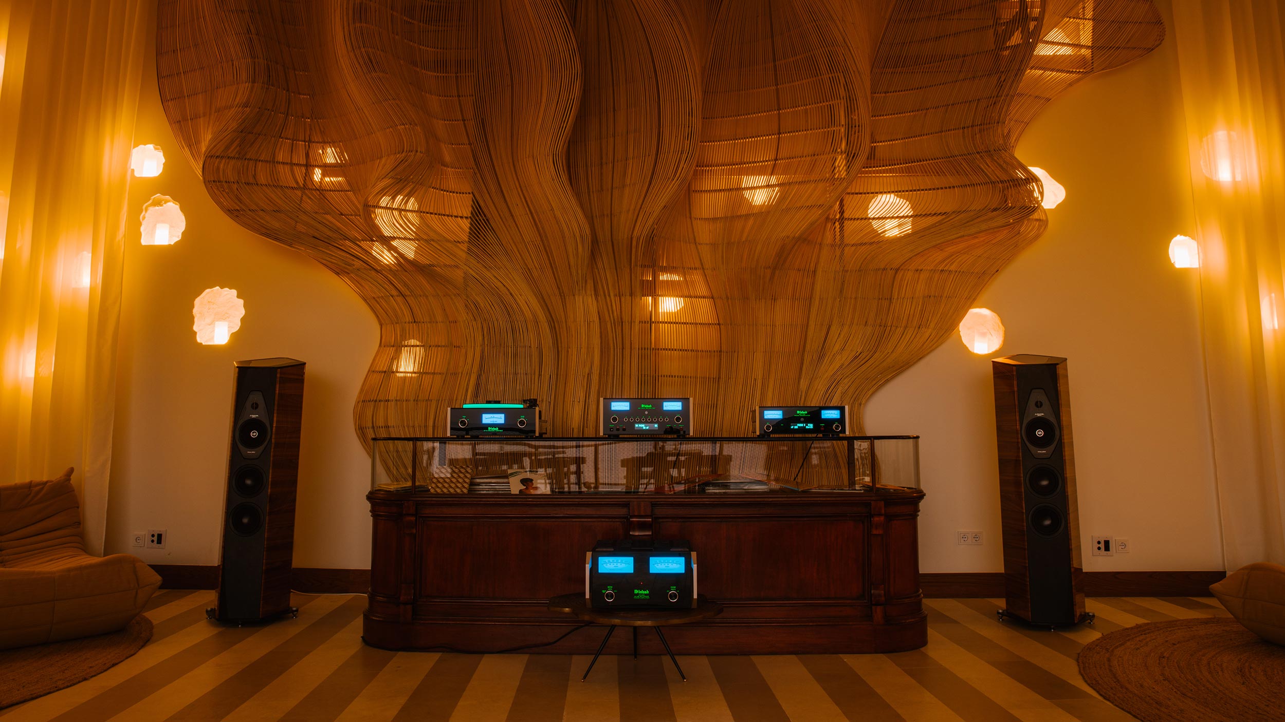 High-end stereo system with glowing blue meters in front of a sculptural wood wall