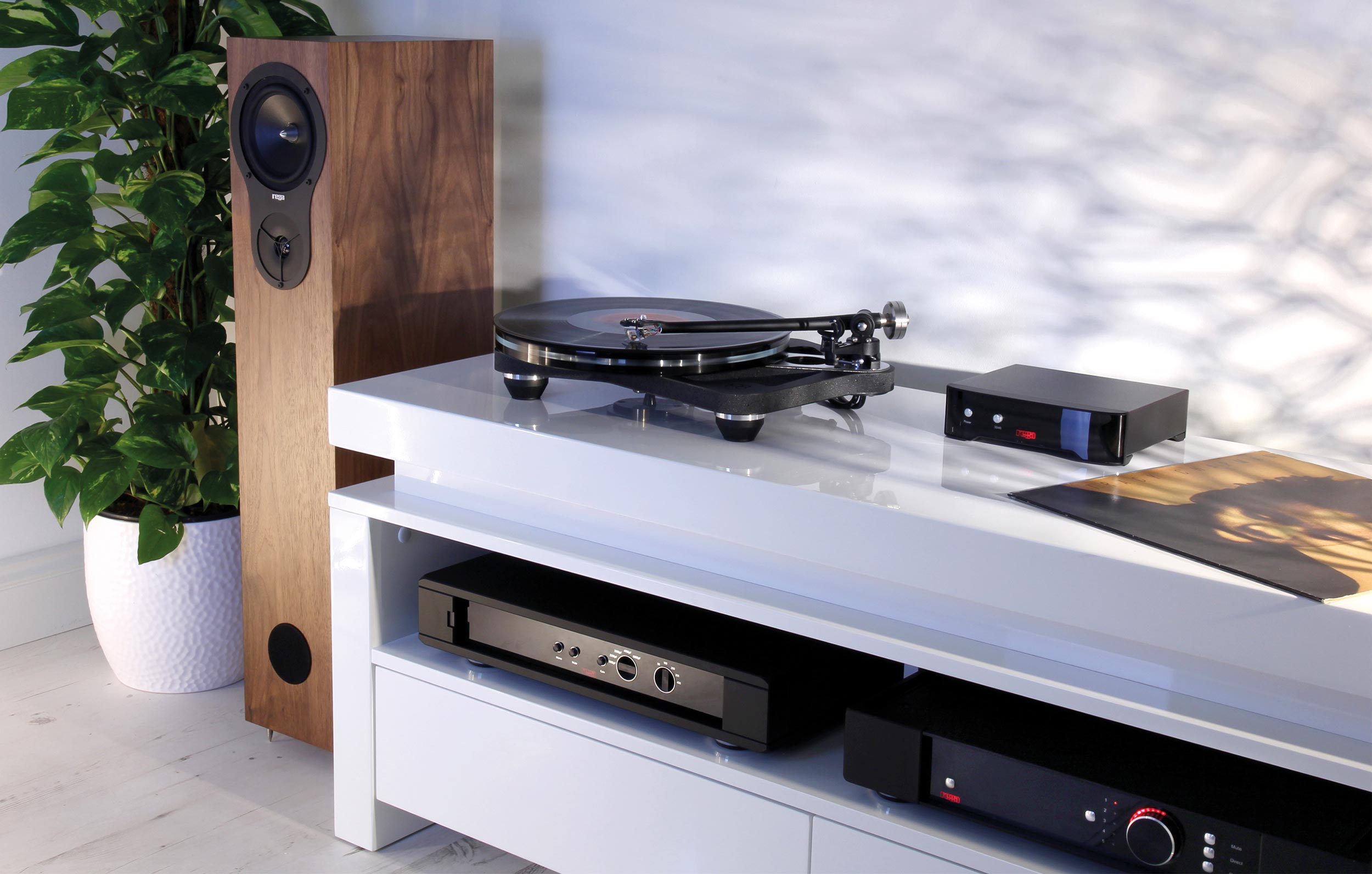 Turntable and audio equipment on a white cabinet beside a wooden speaker