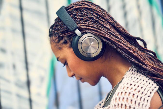 Woman wearing over ear headphones while looking down outdoors