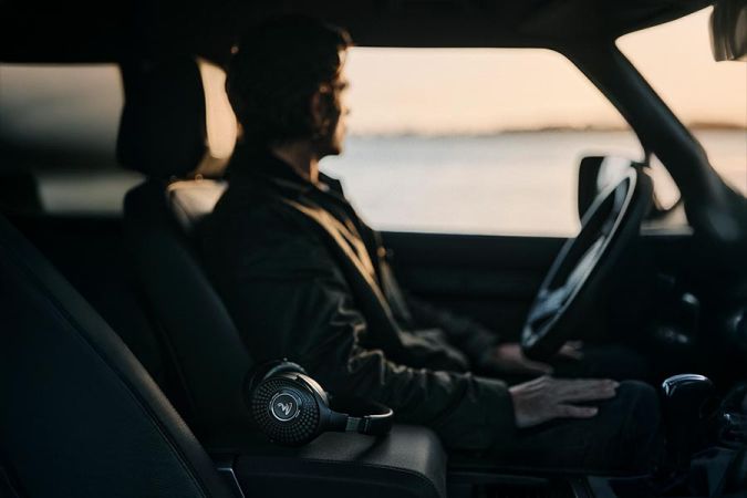 Black headphones resting on the center console of a car with a driver