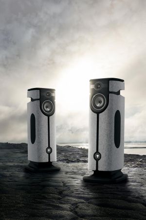 Pair of high-end speakers on a rocky surface with the sun shining through clouds