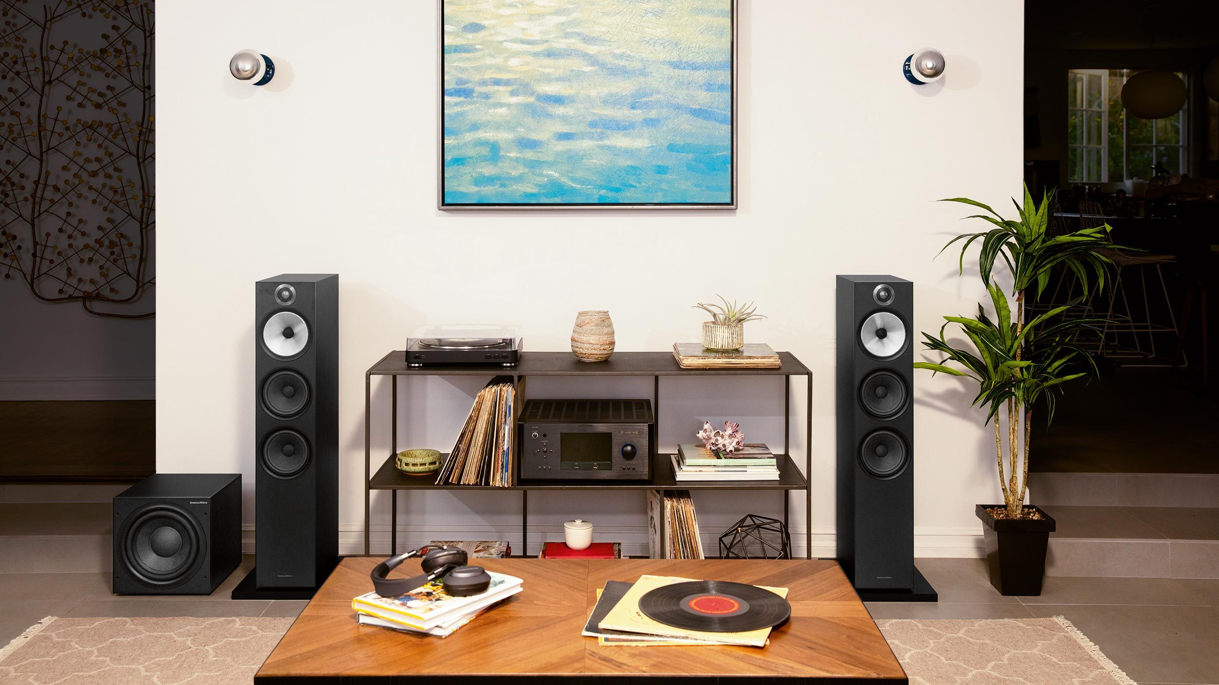 A high-end audio setup featuring large floor-standing speakers, a record player, and various vinyl records organized on a modern shelf.